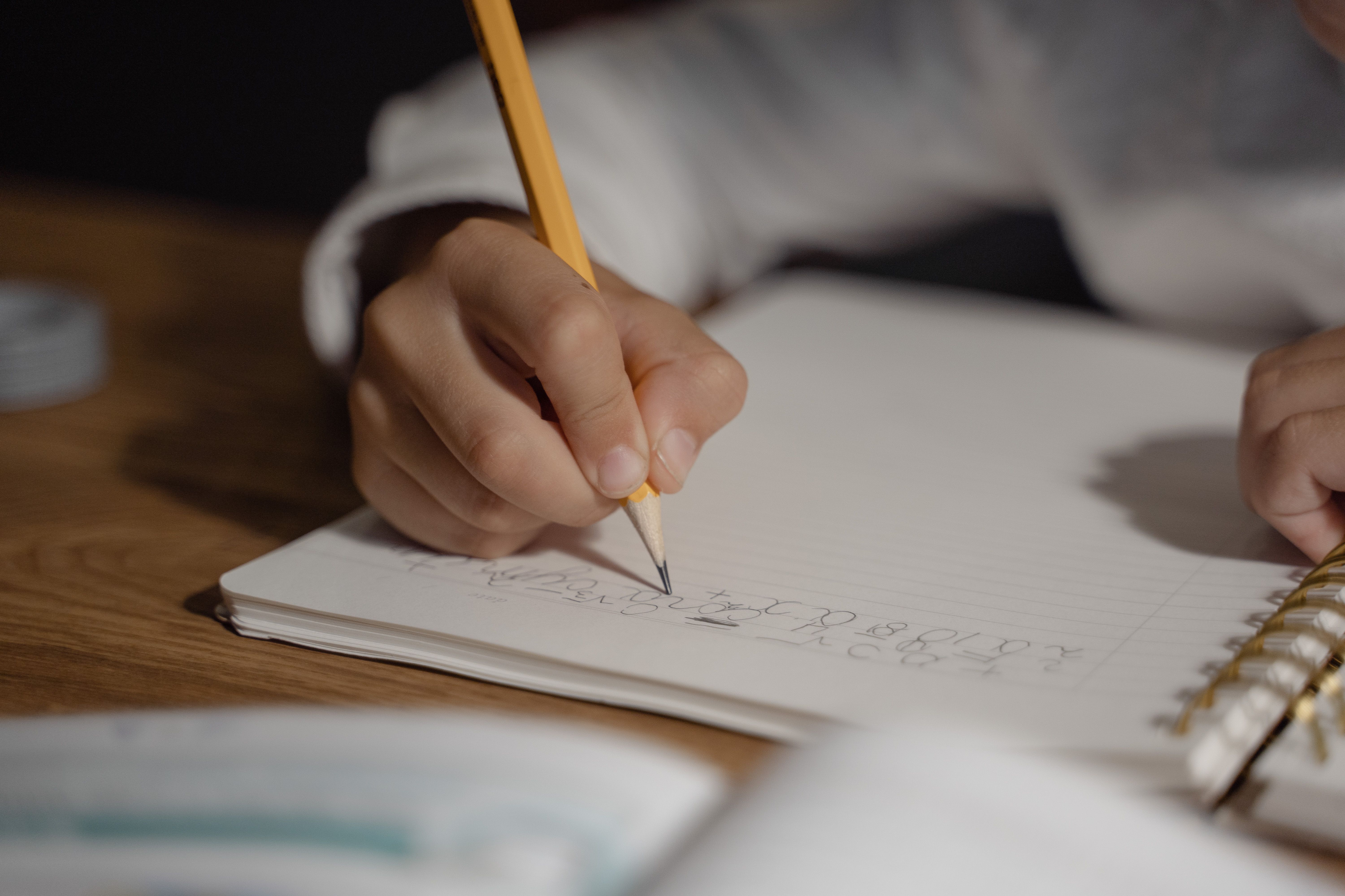 Élève écrivant au crayon dans un cahier